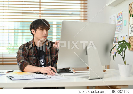 Portrait of male creative website designer working on new project, planning new website wireframe at creative office Portrait of male creative website designer working on new project, planning new website wireframe at creative office 100887102
