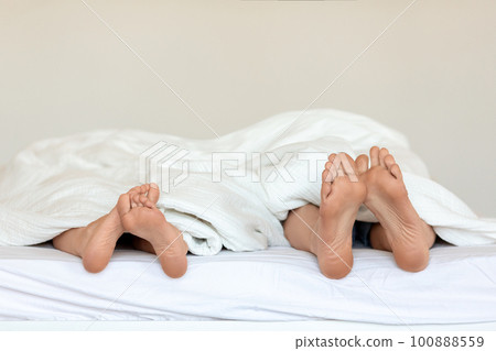 A couple's legs entangled in bed, capturing the intimacy of their moment together. A couple's legs entangled in bed, capturing the intimacy of their moment together. 100888559