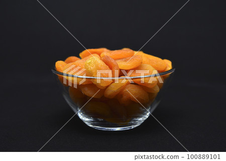 Juicy dried apricots in a glass bowl. Dried apricot fruit halves without a stone. 100889101
