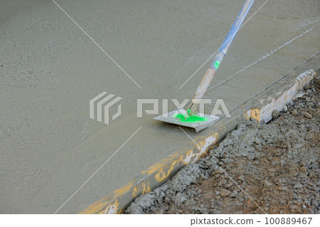 Construction company employee forms corners on freshly cement floor using stainless steel edger Construction company employee forms corners on freshly cement floor using stainless steel edger 100889467