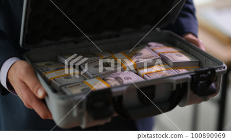Banker holding suitcase with many dollar bills closeup Banker holding suitcase with many dollar bills closeup 100890969