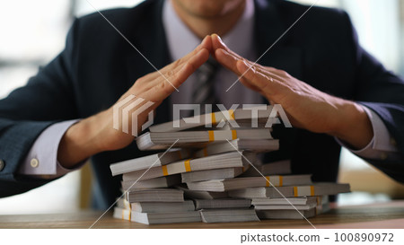 Businessman banker making roof over stacks of money with hands closeup 100890972