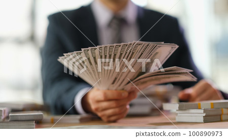 Businessman banker holding fan of dollar bills in hand closeup Businessman banker holding fan of dollar bills in hand closeup 100890973