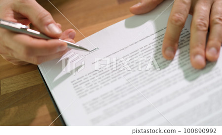 Hands of businessman with pen signing contract document at table closeup Hands of businessman with pen signing contract document at table closeup 100890992