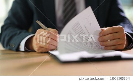 Businessman leafing through documents and signing contract for business deal at work in office closeup 100890994