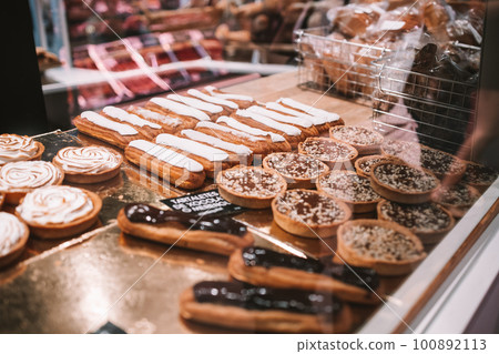 a display case filled with lots of different types of cakes and pies on display in a bakery or deli or bakery shop front view of cakes and frosted with frosting on the shelves. a display case filled with lots of different types of cakes and pies on display in a bakery or deli or bakery shop front view of cakes and frosted with frosting on the shelves. 100892113