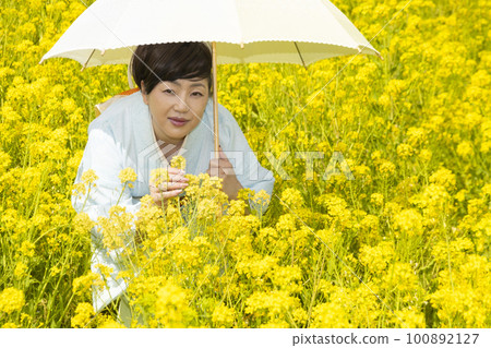 Japanese woman in a beautiful yellow flowers field 100892127