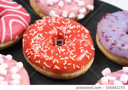 Donuts with red and pink glaze. Lots of donuts, sweet and delicious food 100892255