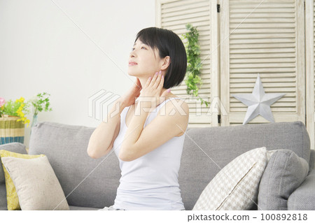 一個女人在客廳裡做頸部自我按摩 100892818