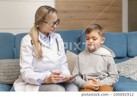 Pediatrician doctor examining sick child in face mask. Ill boy in healthPediatrician examines a sick child. Sick boy in the clinic. Children's home treatment of the virus. 100892912