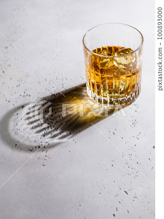 Whiskey in crystal glass with ice cubes and black shadow. Whiskey in crystal glass with ice cubes and black shadow. 100893000