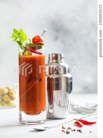 Bloody mary cocktail in highball glass with shaker and spoon on light bar board with olives Bloody mary cocktail in highball glass with shaker and spoon on light bar board with olives 100893015