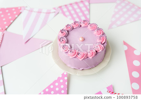 Delicate lavender pink bento cake on a plate against a background of flags for a party. Celebration, happy day. Delicate lavender pink bento cake on a plate against a background of flags for a party. Celebration, happy day. 100893758