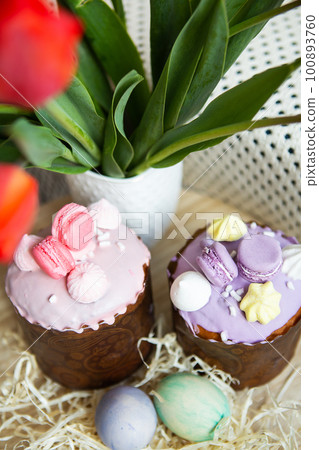 Colorful Easter eggs lie together with Easter pastries decorated with colored chocolate on a wooden table. Easter holiday. Colorful Easter eggs lie together with Easter pastries decorated with colored chocolate on a wooden table. Easter holiday. 100893760