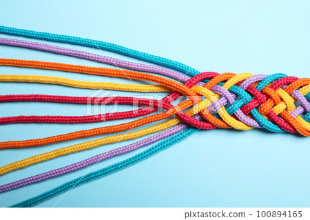 Braided colorful ropes on light blue background, top view. Unity concept Braided colorful ropes on light blue background, top view. Unity concept 100894165