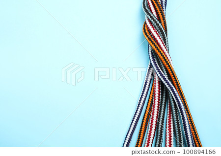 Top view of twisted colorful ropes on light blue background, space for text. Unity concept 100894166