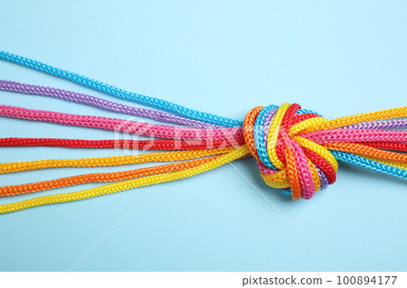 Colorful ropes tied together on light blue background, top view. Unity concept 100894177