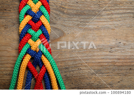 Top view of braided colorful ropes on wooden background, space for text. Unity concept Top view of braided colorful ropes on wooden background, space for text. Unity concept 100894180