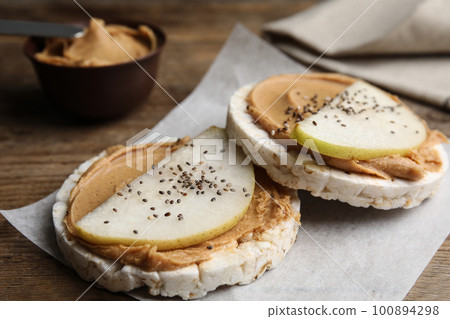 Puffed rice cakes with peanut butter and pear on wooden table 100894298