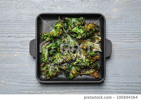 Tasty baked kale chips on light grey wooden table, top view 100894364