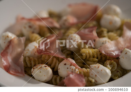 Pesto fusilli with mozzarella and coppa ham on white plate Pesto fusilli with mozzarella and coppa ham on white plate 100894610