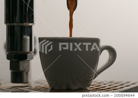 pulling espresso shot with single spout portafilter from coffee machine closeup pulling espresso shot with single spout portafilter from coffee machine closeup 100894644
