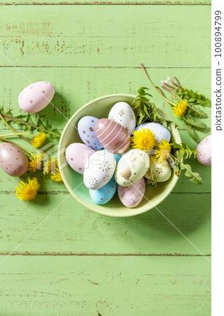Happy Easter Holidays. Handmade Easter colorful eggs and spring flowers dandelions on a rustic wooden table. Easter composition. View from above. Copy space. 100894799
