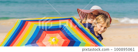 Mother and son on the beach in a hat and beach umbrella 100895061