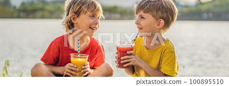 Two boys drink healthy smoothies against the backdrop of palm trees. Mango and watermelon smoothies. Healthy nutrition and vitamins for children 100895510
