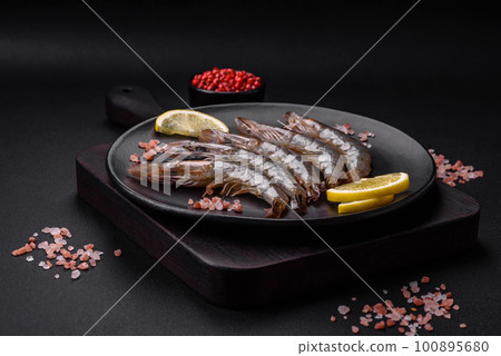 Tiger prawn or langoustine raw with spices and salt on a wooden cutting board 100895680