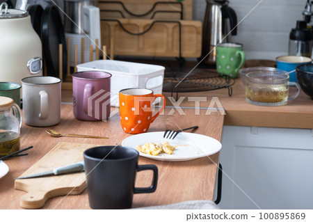 A mess in the kitchen, dirty dishes on the table, scattered things, unsanitary conditions. The dishwasher is full, the kitchen is untidy, everyday life 100895869