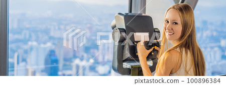Woman looks at Kuala lumpur cityscape. Panoramic view of Kuala Lumpur city skyline evening at sunset skyscrapers building in Malaysia BANNER, LONG FORMAT 100896384