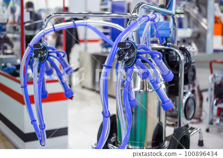 Teat cups of automated cow milking suction machine at exhibition: close up 100896434
