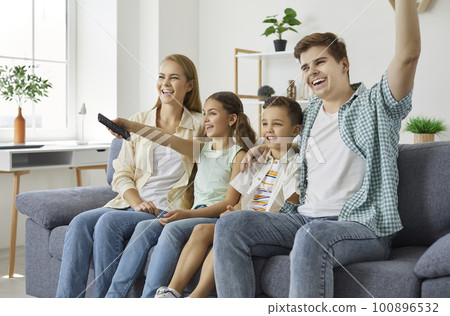 Happy family are sitiing on couch smiling and watching TV together at home in weekend. Happy family are sitiing on couch smiling and watching TV together at home in weekend. 100896532