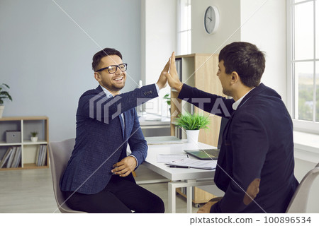 Two happy young people make a business deal, smile and give each other high fives 100896534