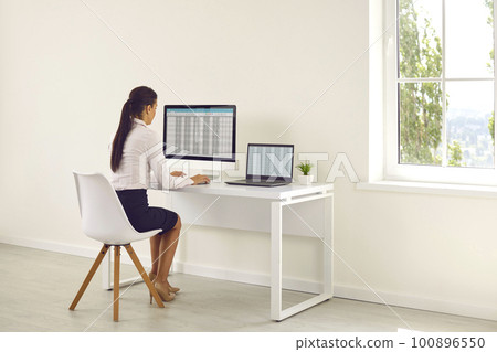 Woman financial manager working on spreadsheets on computers and calculating balance Woman financial manager working on spreadsheets on computers and calculating balance 100896550