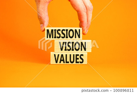 Mission vision values symbol. Concept words Mission Vision Values on wooden blocks on a beautiful orange table orange background. Businessman hand. Business mission vision values concept. Copy space. Mission vision values symbol. Concept words Mission Vision Values on wooden blocks on a beautiful orange table orange background. Businessman hand. Business mission vision values concept. Copy space. 100896811