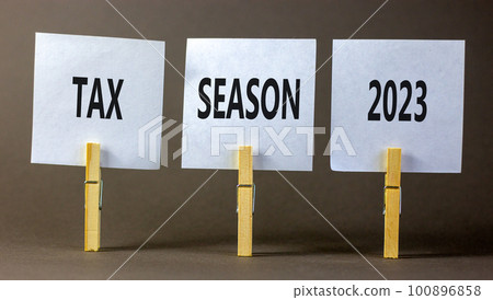 Tax season 2023 symbol. Concept words Tax season 2023 on white paper on clothespin on a beautiful grey table grey background. Business Tax season 2023 concept. Copy space. Tax season 2023 symbol. Concept words Tax season 2023 on white paper on clothespin on a beautiful grey table grey background. Business Tax season 2023 concept. Copy space. 100896858