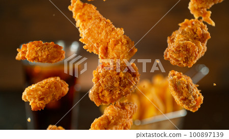 Freeze Motion Shot of Flying Fresh Fried Chicken Wings or Strips, Close-up Freeze Motion Shot of Flying Fresh Fried Chicken Wings or Strips, Close-up 100897139