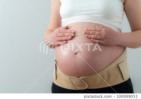 Belly of pregnant woman in bandage. Orthopedic abdominal support belt 100899031