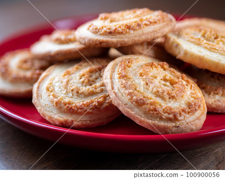 Sugar spiral biscuits on red plate on wooden table. Homemade sweet cookies. Pastry concept 100900056
