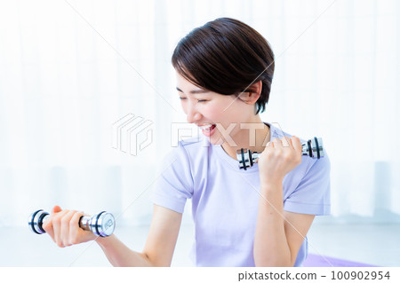 Middle woman training with dumbbells 100902954