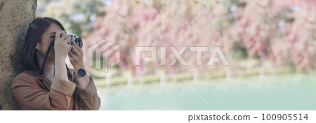 Banner Asian Women with vintage film camera take a photo. Panorama female photographer look at photo from professional camera outdoor. Young woman shooting photo in green nature park with copy space Banner Asian Women with vintage film camera take a photo. Panorama female photographer look at photo from professional camera outdoor. Young woman shooting photo in green nature park with copy space 100905514