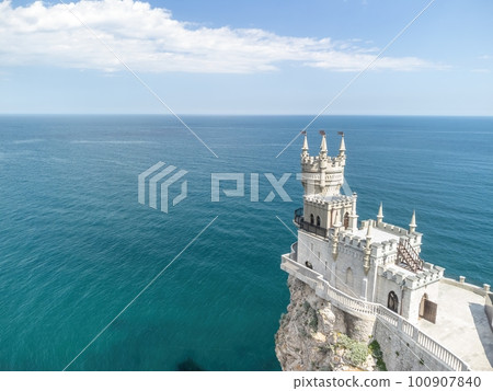 Crimea Swallow's Nest Castle on the rock over the Black Sea. It is a tourist attraction of Crimea. Amazing aerial view of the Crimea coast with the castle above abyss on sunny day. 100907840