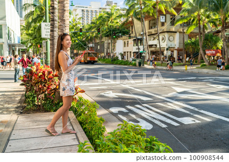 Waikiki tourist woman walking in Honolulu city street using mobile phone. Hawaii Summer vacation destination 100908544