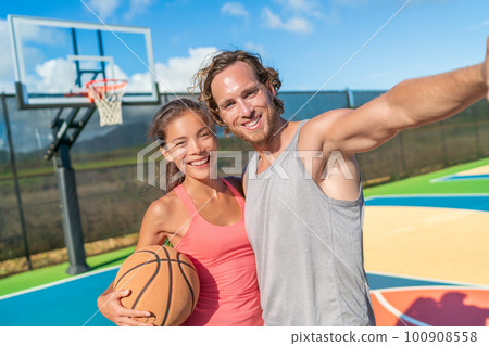 Basketball selfie woman and man friends playing recreational game happy having fun with ball on outdoor court Basketball selfie woman and man friends playing recreational game happy having fun with ball on outdoor court 100908558