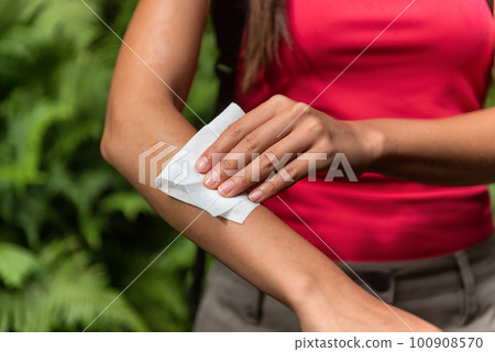 Zika and West Nile viruse mosquito woman using repellent wipes wiping arm with wet wipe applying bug spray chemical product Zika and West Nile viruse mosquito woman using repellent wipes wiping arm with wet wipe applying bug spray chemical product 100908570