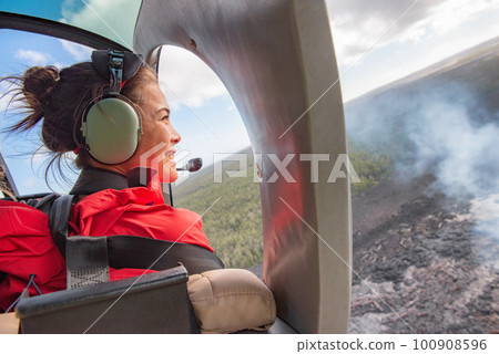 Helicopter doors off ride adventure travel Asian woman tourist happy looking at landscape of volcanic eruption above volcano fumes in Big Island, Hawaii 100908596