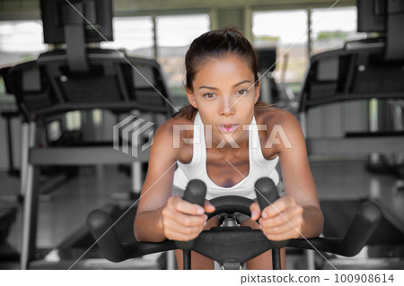 Gym fitness class fit woman riding spin bike doing hiit exercise cycling doing cardio workout biking on indoors gym bike. Girl cyclist working out interval training on bicycle. weight loss 100908614