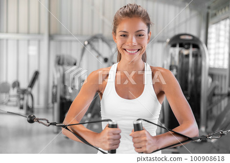 Fitness woman working out in gym with cable tower. Fit Asian girl training toned arms and body Fitness woman working out in gym with cable tower. Fit Asian girl training toned arms and body 100908618